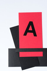 the letter A on red card and black paper shapes on white