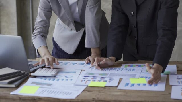 Investment advisor 2 business people analyze company financial statements working with document graphs for stock market, office, tax and project team of data analysts working with tablet computers.