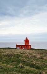 red lighthouse on the coast - obrazy, fototapety, plakaty