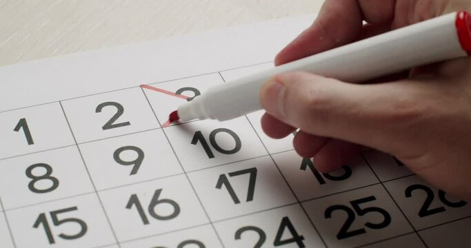 Man's hand Write down the 3th day on the paper calendar using a red pen. Very important date in the calendar. Signing a day on a calendar. Calendar 3th date of the month cut.