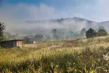 Fototapeta na wymiar a wooden shed on foggy meadow in Ukrainian village