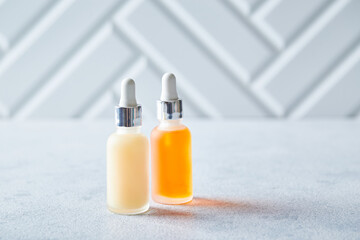 Glass bottles with face or body skin care products on a light background. Self-care, cosmetics,...