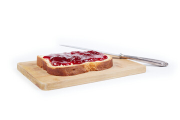 a piece of white bread with strawberry jam and a silver knife, isolated on white background