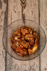 Pieces of chicken in sauce in a glass plate on a wooden table.