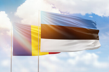 Sunny blue sky and flags of estonia and romania