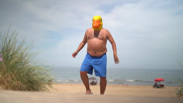 Fat man with duck mask on the beach jumping