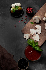 Products for cooking pizza and salad on a dark background. vegetables, sauces and herbs with spices. Place for text.