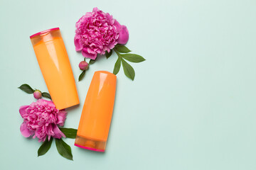Shampoo and conditioner with peony flower and comb on color background, top view
