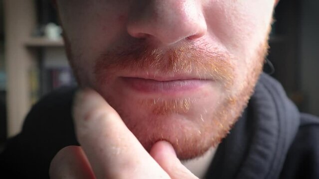 pessoa de genero masculino com barba ruiva pensativo em suas expressoes faciais levando a m&atilde;o ao rosto