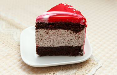 A serving of delicious sweet cake covered in red icing lies in a dessert plate