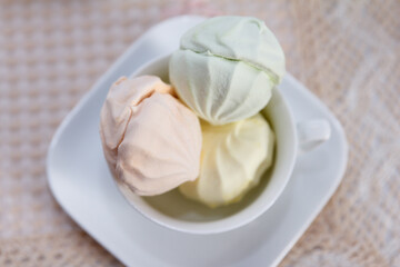 Sweet fresh multicolored air marshmallow lies on a serviced table in saucers