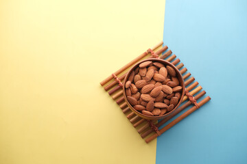 top view of almond nut in a wooden bowl on color background 