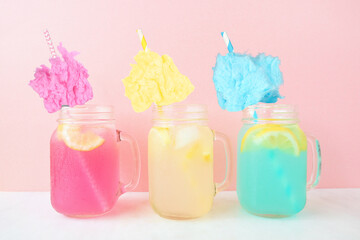 Summer cotton candy lemonade drinks. Three colors in mason jar glasses against a pastel pink background.