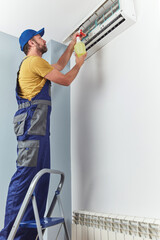 Repairman cleaning and fixing indoors AC unit.