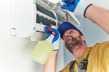 Repairman cleaning and fixing indoors AC unit.