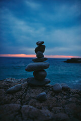 Silhouette of balanced zen stones on the ocean beach ant sunset sunrise time.