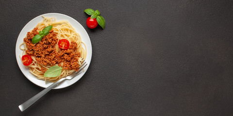 Pasta Spaghetti Bolognese in white plate on dark background. Bolognese sauce is classic italian...