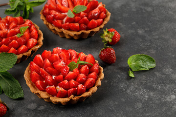 Tarts with Strawberries, cream and mint on slate board and dark background. Cake basket, dessert with strawberries. Sweet pies