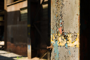 Cracked and aged layers of paint on an iron supporting beam of an abandoned industrial building