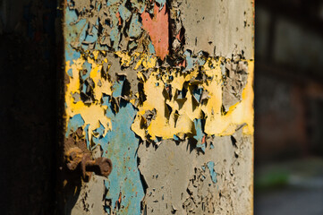Cracked and aged layers of paint on an iron supporting beam of an abandoned industrial building
