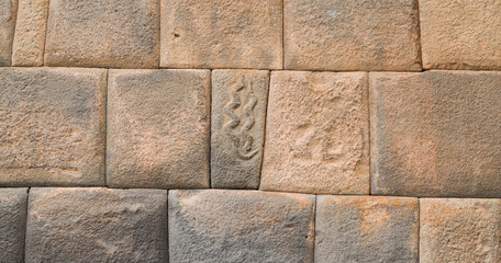 Megalithic stone walls with snake carvings, craftmenship in ancient city of cusco.