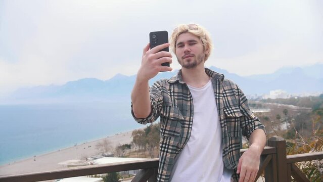 Young stylish man takes selfie on the background of the sea