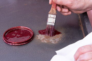 Persona que pinta una chapa oxidada con pintura antioxidante