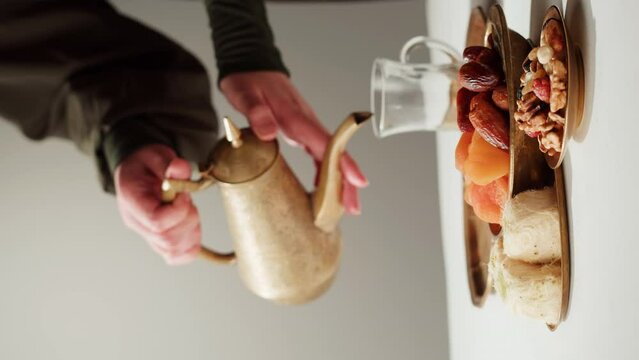 Vertical video of turkish tea and sweets, hot drink in traditional armudu glass close-up. National islamic pastry, treats.