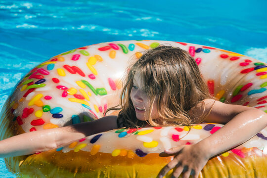 pretty young girl playing with her donut-shaped buoy in the swimming pool