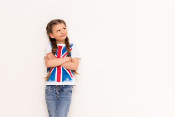 English for school children. A little girl with the flag of Great Britain leans on your advertisement on a white isolated background.