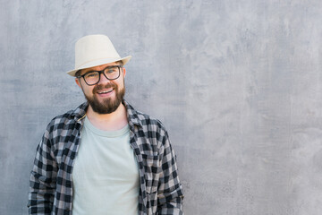 Handsome guy tourist looking happy wearing straw hat for travelling, standing against concrete wall background with copy space