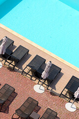 View of the swimming pool with blue water, sun loungers and umbrellas.
