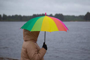A woman with a multicolored umbrella on the street during the rain.