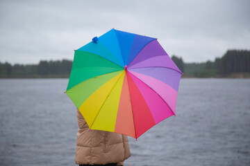 A woman with a multicolored umbrella on the street during the rain.