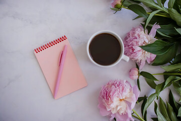 Cup of coffee, peony flower, notebook on a light background