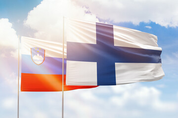 Sunny blue sky and flags of finland and slovenia