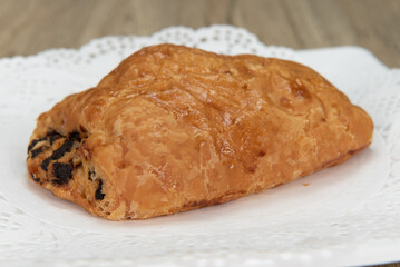 Tempting fresh from the oven chocolate croissant from the bakery served on a plate