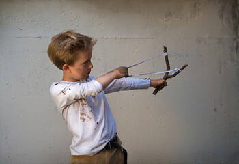 Dirty boy aiming with a slingshot - obrazy, fototapety, plakaty