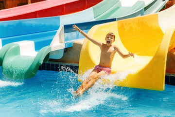  Boy having funin water park. A kid is slithering down the water slide and making splashes. 