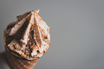 Ice cream cone on grey wall background with copy space. Caramel ice cream in waffle. Creamy dessert. Refreshing cold dessert. Melting ice cream. Summer lifestyles. Sweet food concept. 