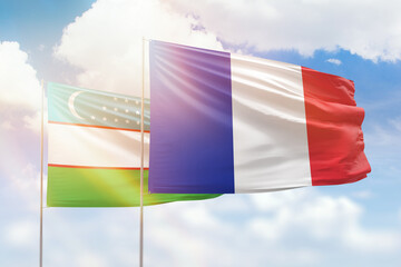Sunny blue sky and flags of france and uzbekistan