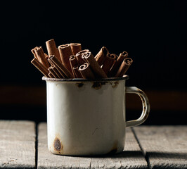 dry brown cinnamon sticks in a metal old mug, culinary spice