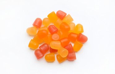 Close-up texture of orange and yellow multivitamin gummies in the form of bears on white...