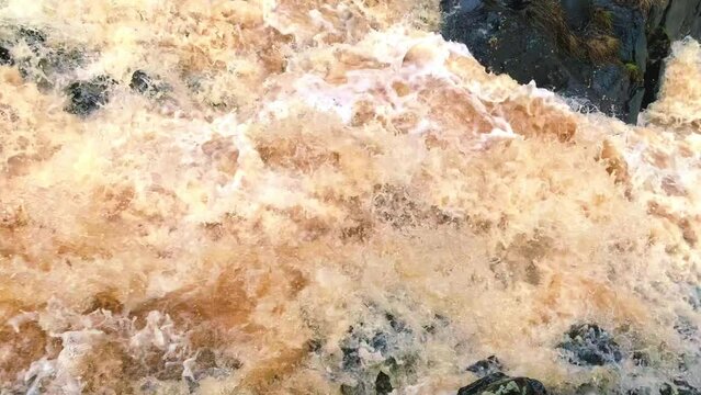 Mountain river with dark brown water with a rapid flow between stones. High quality 4k footage