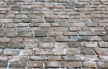 The grey snow-covered paving stones close up. The texture of the old dark stone. Road surface. Vintage, grunge.