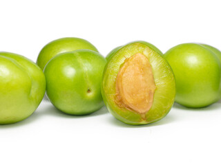 Green cherry plum on a white background. Fruit for making tkemali sauce. Diet food. Useful fruits.  Juicy cut green plum
