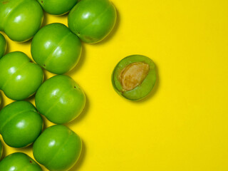 Green cherry plum on a yellow background. Fruit for making tkemali sauce.   Useful fruit. Sweet and sour fruit. Juicy cut green plum