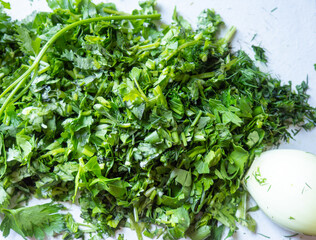 Various finely chopped greens from the garden. Parsley, dill, cilantro. Juicy, fresh herbs. Healthy food. Vitamins on the table. Seasoning for food. Cooking.