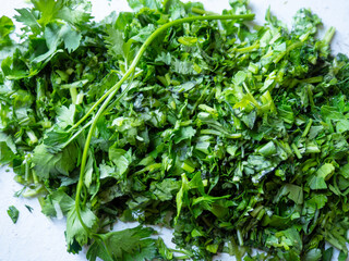 Various finely chopped greens from the garden. Parsley, dill, cilantro. Juicy, fresh herbs.  Vitamins on the table. Seasoning for food. Cooking.