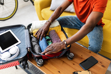 Close up hands of young african man packing luggage before going on vacation. Travel and vacation...